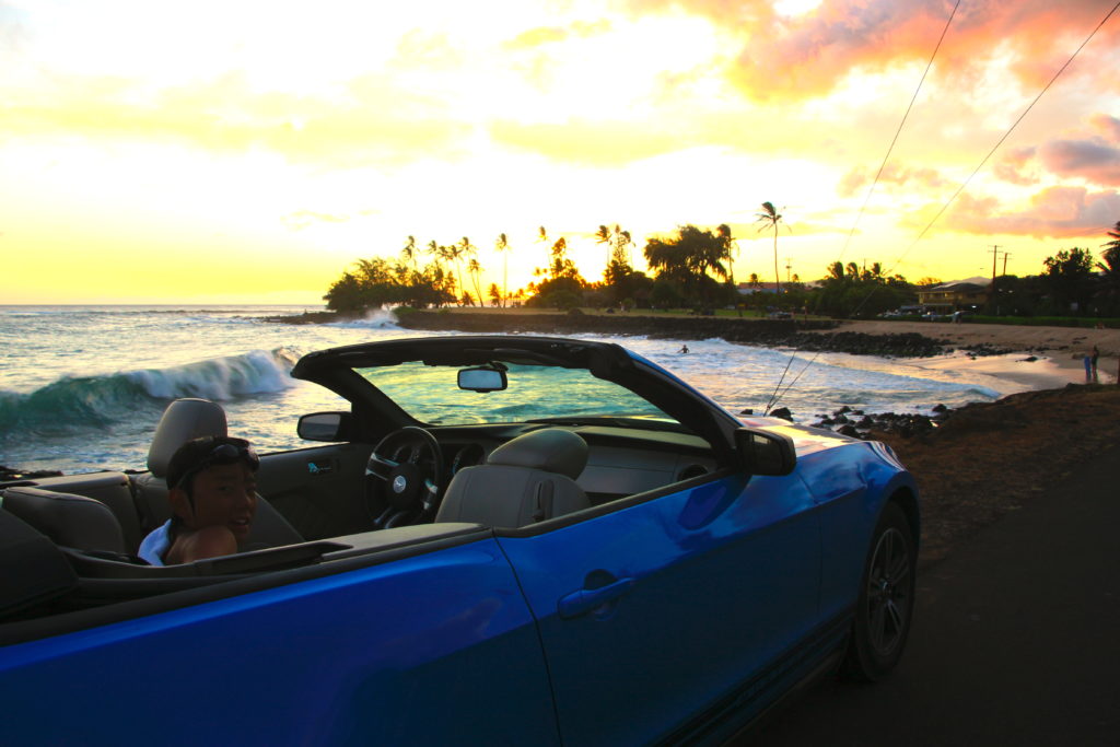 カウアイ島の夕方のビーチでオープンカーに乗って振り向く次男