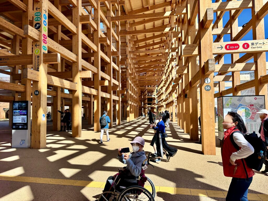 大屋根リングの下を車椅子で通る母。スマホで写真を撮ってます